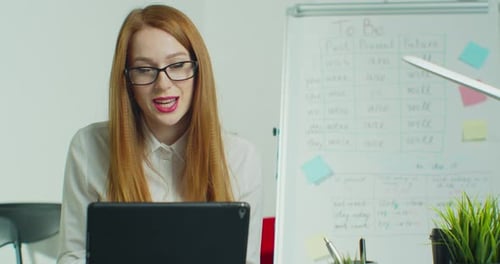 Woman Talks at Laptop in Classroom Setting