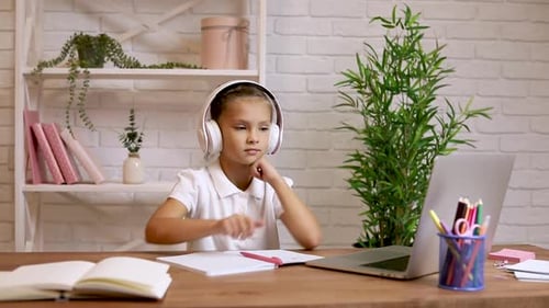 Girl Listens and Writes While Doing Schoolwork
