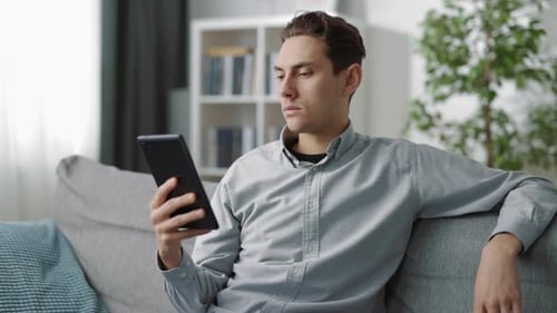 Young Adult Using Tablet on Couch at Home