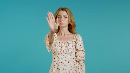 Woman Making Stop Gesture in Front of Blue Background