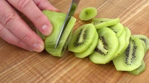Slicing Fresh Kiwi Fruit on Cutting Board