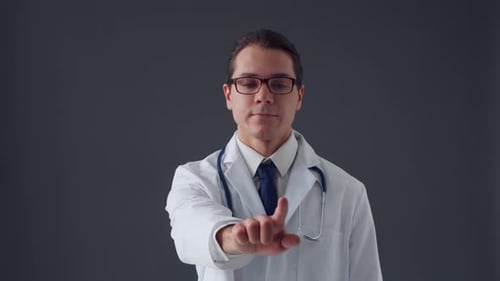 Studio portrait of young professional medical doctor standing over grey background