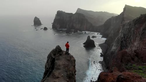 Drone Circle Around Man Hiker Standing on a Dangerous Cliff with Ocean View