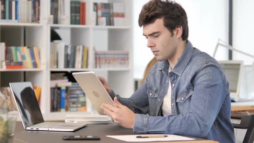 Young Adult Uses Tablet at Office Desk