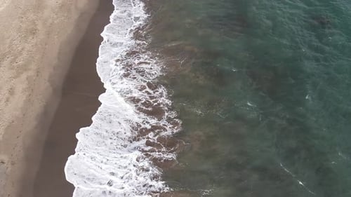 Waves Crashing on Sandy Beach from Above