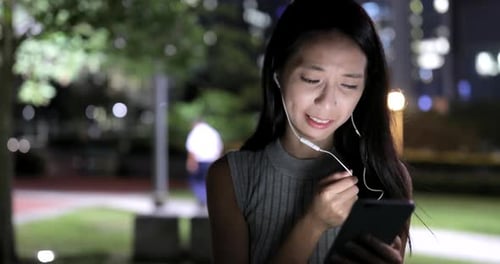 Young Woman Using Smartphone at Night in City