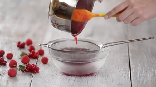 Straining Red Berry Puree in Kitchen Close Up