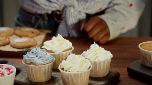 Person decorating cupcakes with blueberries