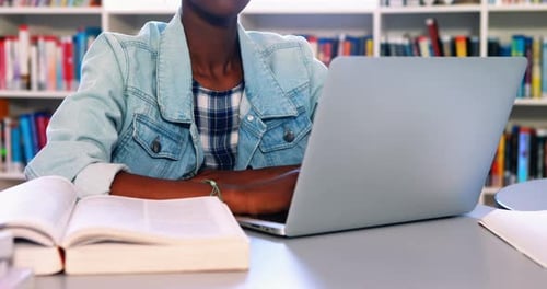 School girl using laptop in library