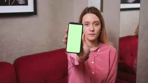 Stock Video Woman Showing Smartphone with Empty Green Screen Chromakey at Home
