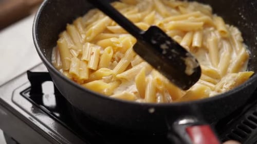 Penne Pasta with Cream Sauce Being Stirred