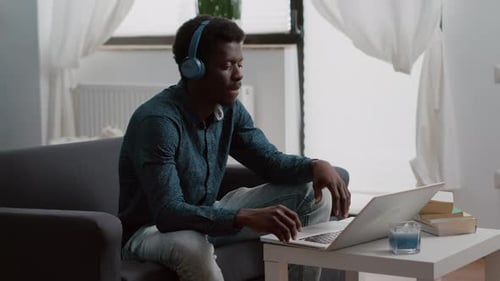 Young Adult Using Laptop with Headphones Indoors
