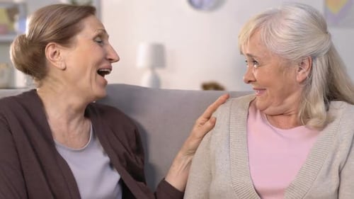 Two Senior Women Laughing Together on Sofa