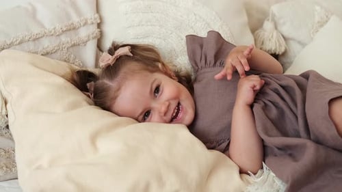 Smiling Girl Lying on Pillows in Bed