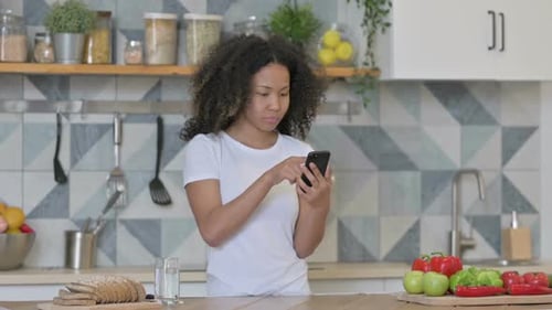 Young Adult Using Phone in Kitchen