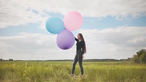 Happy Girl with Big Multicolored Balloons Posing on the Field