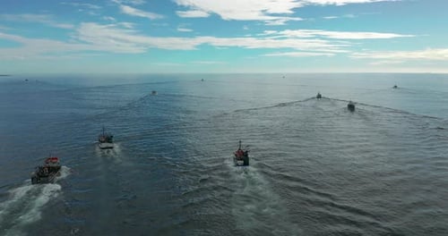 Fishing Boats Sail at Sunset to of Fish on Calm Sea Surface in Summer