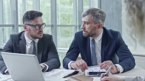 Men Discuss Business Plan in Modern Office