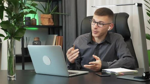 Man vlogger is looking at camera, talking and making live video conference call online using laptop