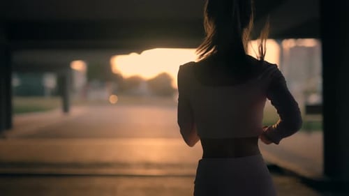 A Young Woman Runner is Training in the Summer Within a City