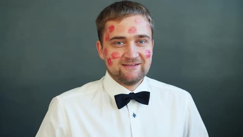 Smiling Man with Lipstick Kisses All Over His Face