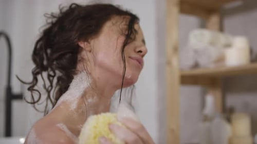 Woman Smiling While Washing Herself With Soapy Sponge