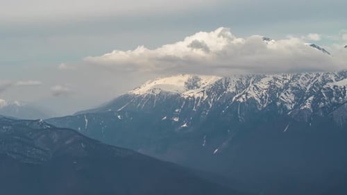 View of Clouds over snowy peaks