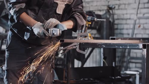 Working at the Construction Plant Cutting Off the Piece of Metal with an Angle Grinder