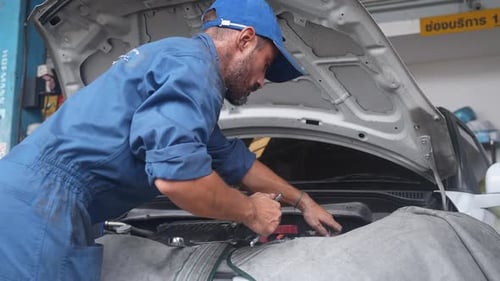 Junger Mann ist Mechaniker, der Motor des Autos in der Garage repariert, Autoservice.