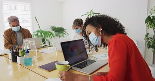 Woman wearing face mask taking notes in office