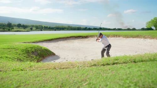 4K Asian senior man hitting golf ball from a bunker on golf course