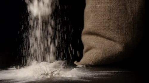 Flour Pours onto Black Surface with Burlap Sack