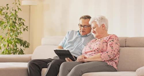 Senior Couple Relaxing on Couch with Tablet Device