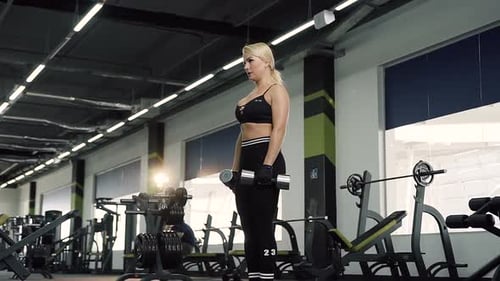 Blonde Woman Doing Dumbbell Exercise in Gym