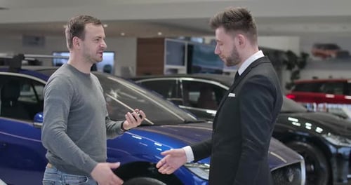 Car Salesman Handing Keys to New Car Owner