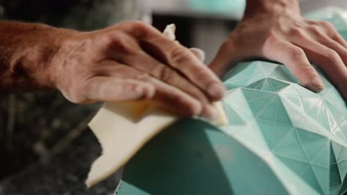 Nahaufnahme: Ein männlicher Maler und Bildhauer wischt das Produkt ab und ordnet die Dinge in der Werkstatt