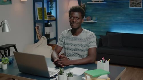 Smiling Young Adult at Desk with Laptop at Home