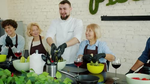 Happy Cookery Teacher Making Salad While Cheerful Women in Aprons Watching Smiling