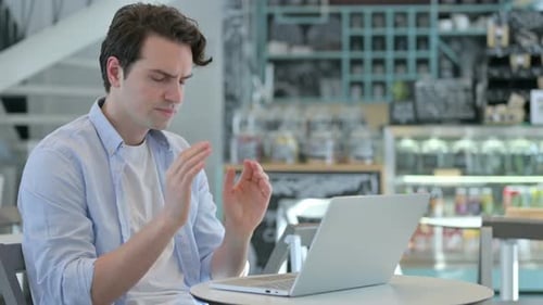Stressed Man Typing on Laptop in Modern Cafe
