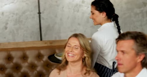 Waitress serving food to friends group 4K 4k