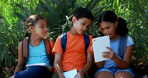 Kids using digital tablet in park