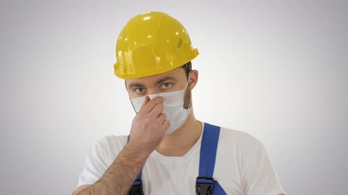 Man in Hard Hat and Face Mask Adjusts Mask