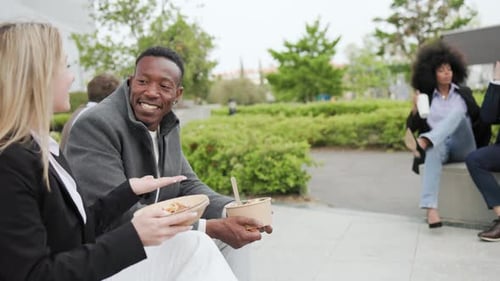 Happy multiracial business people eating takeaway food during lunch break meeting outside the office