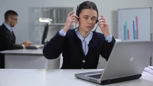 Gerente de llamadas femenino nervioso quitándose los auriculares y cerrando la computadora portátil, día duro