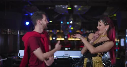 Cheerful Young Caucasian Man and Woman Dancing in Night Club Next To DJ Controller. Handsome Male DJ