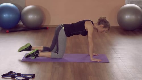 Woman Exercises Indoors Doing Donkey Kicks