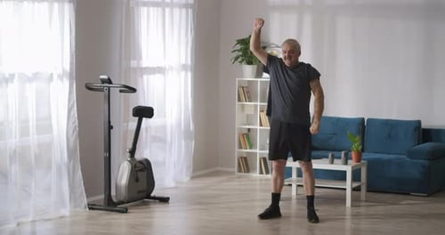 Homem idoso está fazendo ginástica em seu apartamento no domingo de manhã cuidando da saúde das articulações