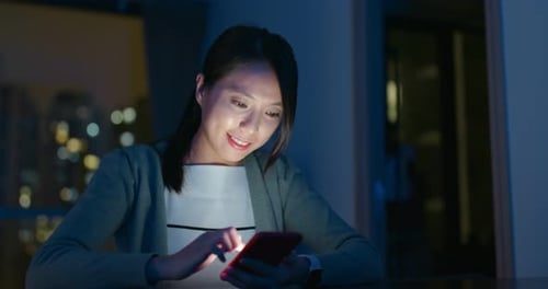 Woman Uses Smartphone at Night in Apartment