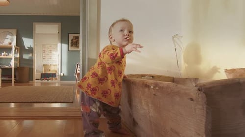 CU - Un mignon bébé de 9 mois attrape un morceau de bois dans une boîte et le met dans sa bouche