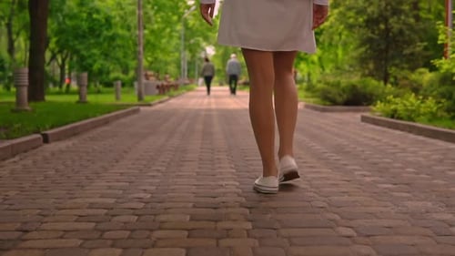 Woman Walks Along a Path in the Park